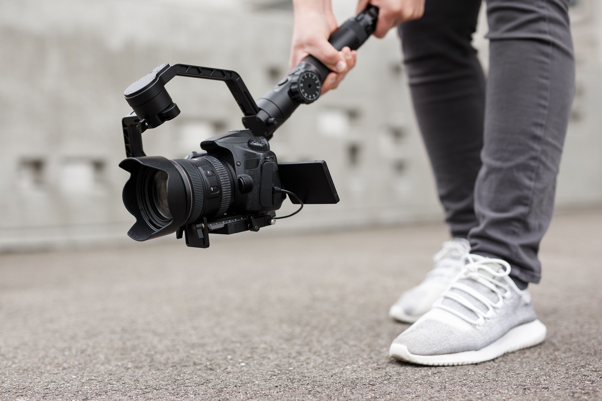 videography, filmmaking and creativity concept - close up of modern dslr camera on 3-axis gimbal stabilizer in male hands